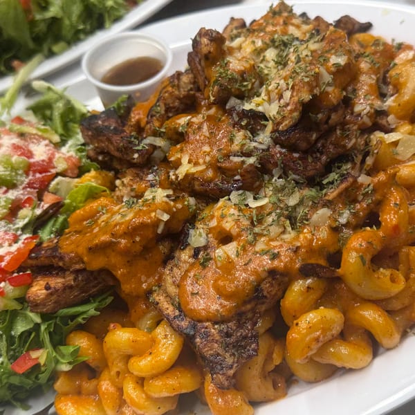 Grilled chicken and macaroni with creamy orange sauce, cheese, herbs, and a fresh side salad.