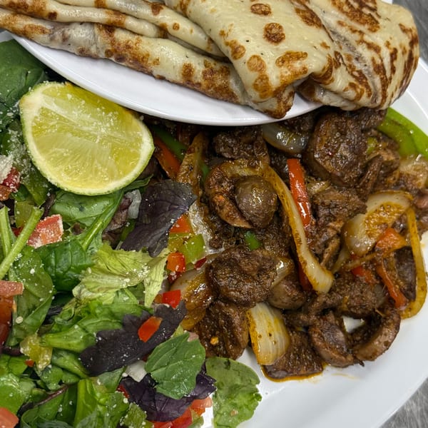 Savory crepes, sautéed meat with peppers and onions, and a fresh green salad with lime.