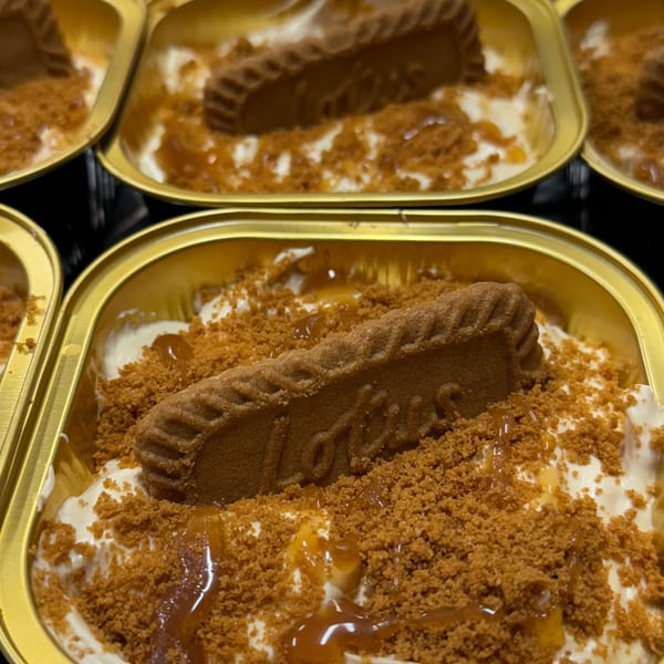 Multiple creamy desserts in golden containers topped with Lotus Biscoff crumbs, caramel, and a biscuit.